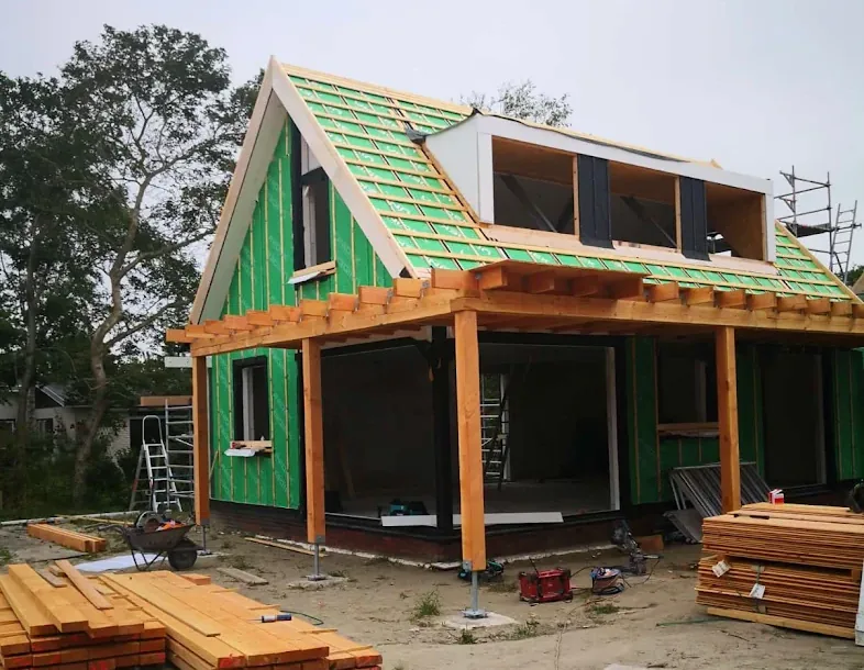 Woning in aanbouw met dakkapel, houten spanten en overstek